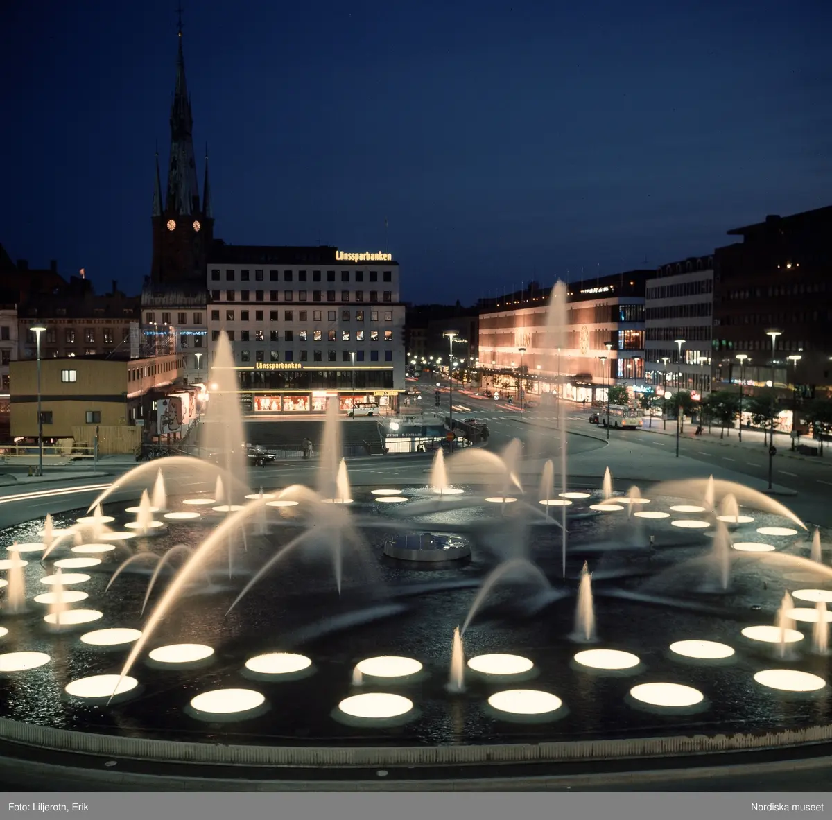 Sergels torg, Stockholm, kväll. Utsikt mot entrén till T-centralen, Åhlénshuset och Klara kyrka.