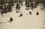 Fyra soldater med skidor sitter i snön. I bakgrunden gles vinterskog.