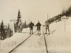 Landsgränsen mellan Sverige och Norge. Fyra soldater på skidor står på järnvägsrälsen mellan två skyltar med text 