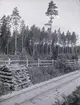 Ett järnvägsspår, staket och vedtrave i skogen i närheten av Tuna gård.