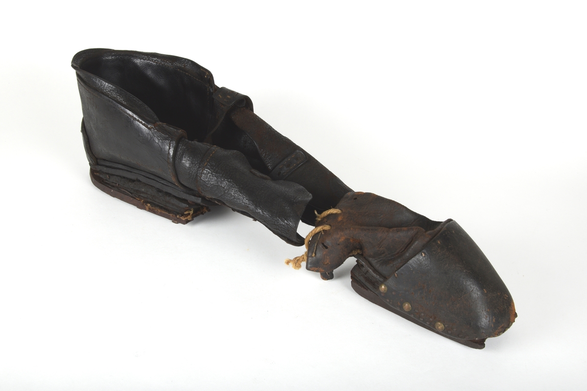 Et par spesialsko med lærreimer som festes til knærne. De består av to deler til kne/legg og to deler til fot/tær. Skoene er laget til en handikappet mann som gikk på knærne.

Leggskoene har jern på undersiden, festet med 6 hesteskosømmer. To spenner med reimer for festing til legg.

Tåskoene har to jern på undersiden, på den ene festet med 7 hesteskosømmer. Den andre har 6 hesteskosømmer og tau for snøring.