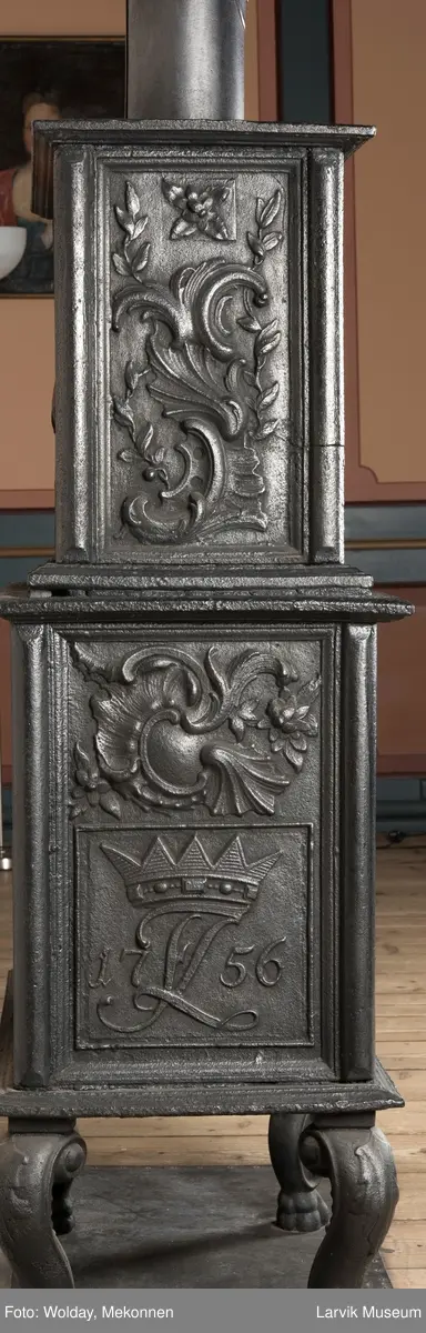 Ovn i  2 etasjer. 
Rokokko, jfr. nr 411 i Norsk Jernskulptur b II 
1. etasje langside: Mars sitter på en kanon med sverd i høyre hånd. Riflet bunn.
1 etasje kortside: Øverst: Rokokko-ornament, nederst: Grevekrone monogram. FL og 1756 
nederst: ovnsdør 2 hengsler ovalt askebrett med profilert kant.
2.etasje langside: Fyldig rokokko-ornament. med blomster. Uregelemessig portalåpning. 
2. etasje kortside: Rokokko-ornament, 
Ovnen har sungne ben m/dyreføtter