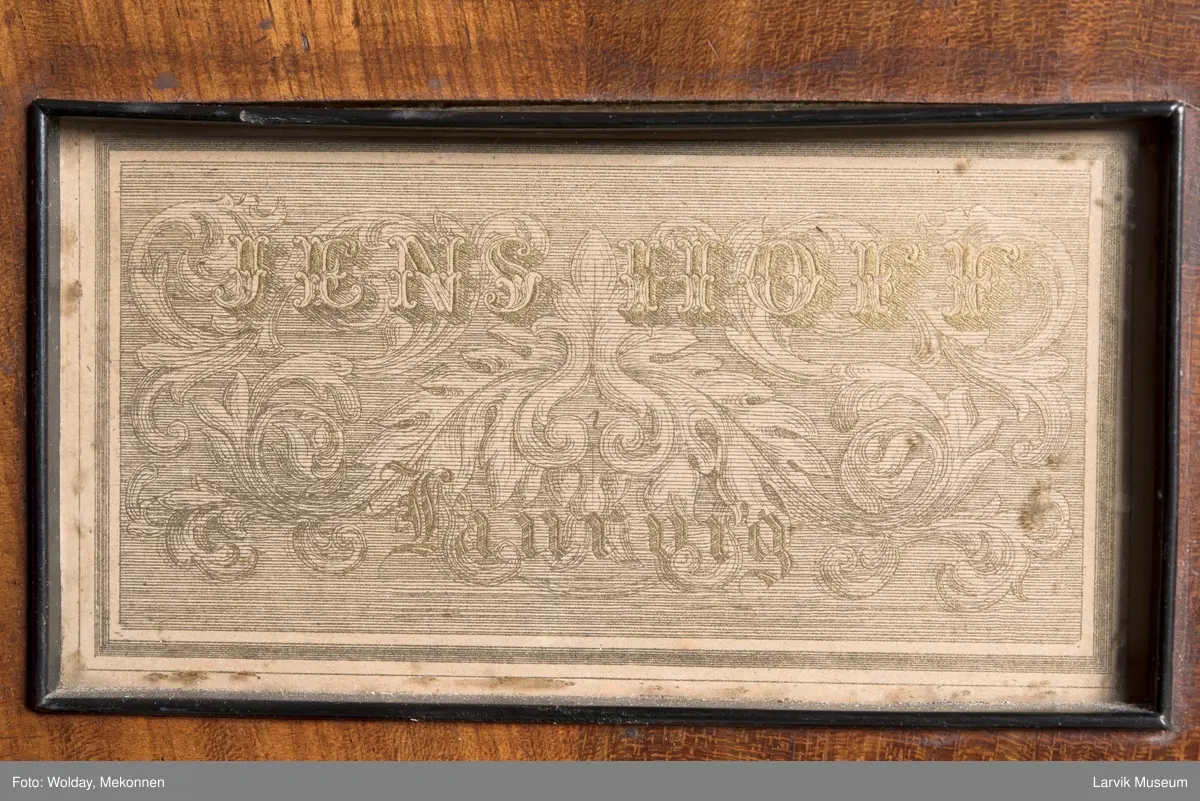 Rektangulært, stekt svugne ben tilnærmet. c-form korte bindn. under lokkplate med glass hvor signert Jens Hoff, Laurvig en pedal festet til pedalfot(?)