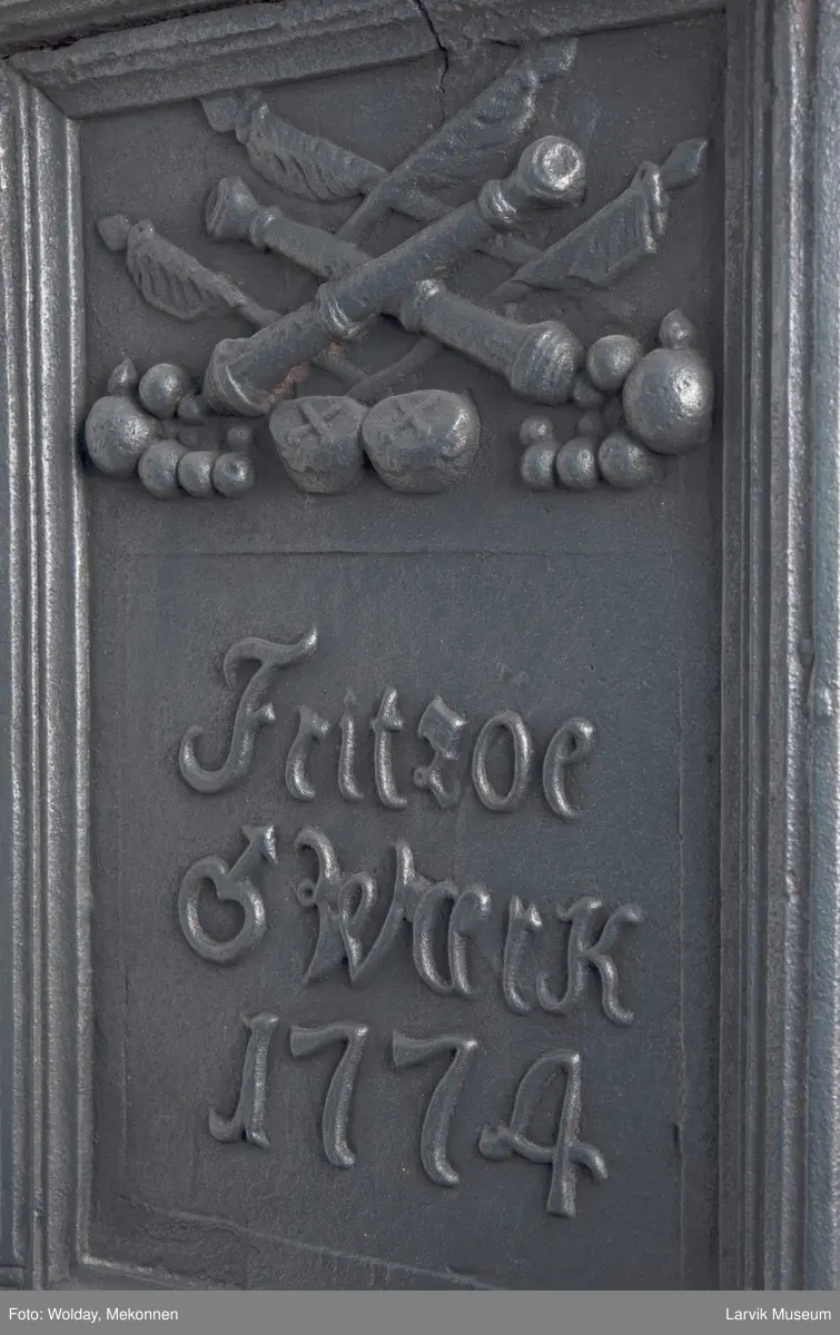 1. etasje langside: Chr. VII's byste, rosetter, meander ramme.
1. etasje kortside: Krigerske emblemer over Fritzøe Wærk 1774, under krigerske emblemer, dør med gjennombrudd blomstermønster
2. etasje langside: Rundbuet åpning med kanellert ramme, øverst kroningsregaliene, gitret bunn.
2.etasje kortside: kronet C7 på gitret bunn jfr. nr 420 i Norsk Jernskulptur II.