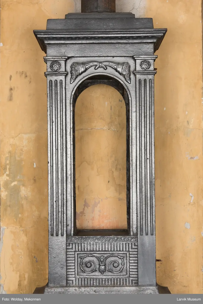 Ovn med avtrappet topp, ovalt, bølget askebrett. 
1. etasje langside: halvsirkelformet. Døren er hengslet i underkant. Over denne på plate står det Fritzøe Wærk. Riflet bunn, lisener med bladverk ved hjørnene. 1. etsje kortside: Rosett, riflet bunn, 
2. etasje langside: Rundbuet åpning, lister til 4 etasjeplater. Over åpning 2 overflødighetshorn, under palmett i riflet ramme. kannelserte pilastre i hjørnene. 2. etasjekortside: Rosett på riflet bunn, bølgemeander.