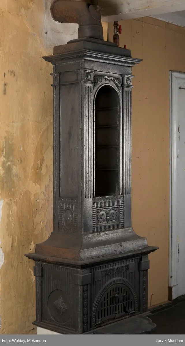 Ovn med avtrappet topp, ovalt, bølget askebrett. 
1. etasje langside: halvsirkelformet. Døren er hengslet i underkant. Over denne på plate står det Fritzøe Wærk. Riflet bunn, lisener med bladverk ved hjørnene. 1. etsje kortside: Rosett, riflet bunn, 
2. etasje langside: Rundbuet åpning, lister til 4 etasjeplater. Over åpning 2 overflødighetshorn, under palmett i riflet ramme. kannelserte pilastre i hjørnene. 2. etasjekortside: Rosett på riflet bunn, bølgemeander.