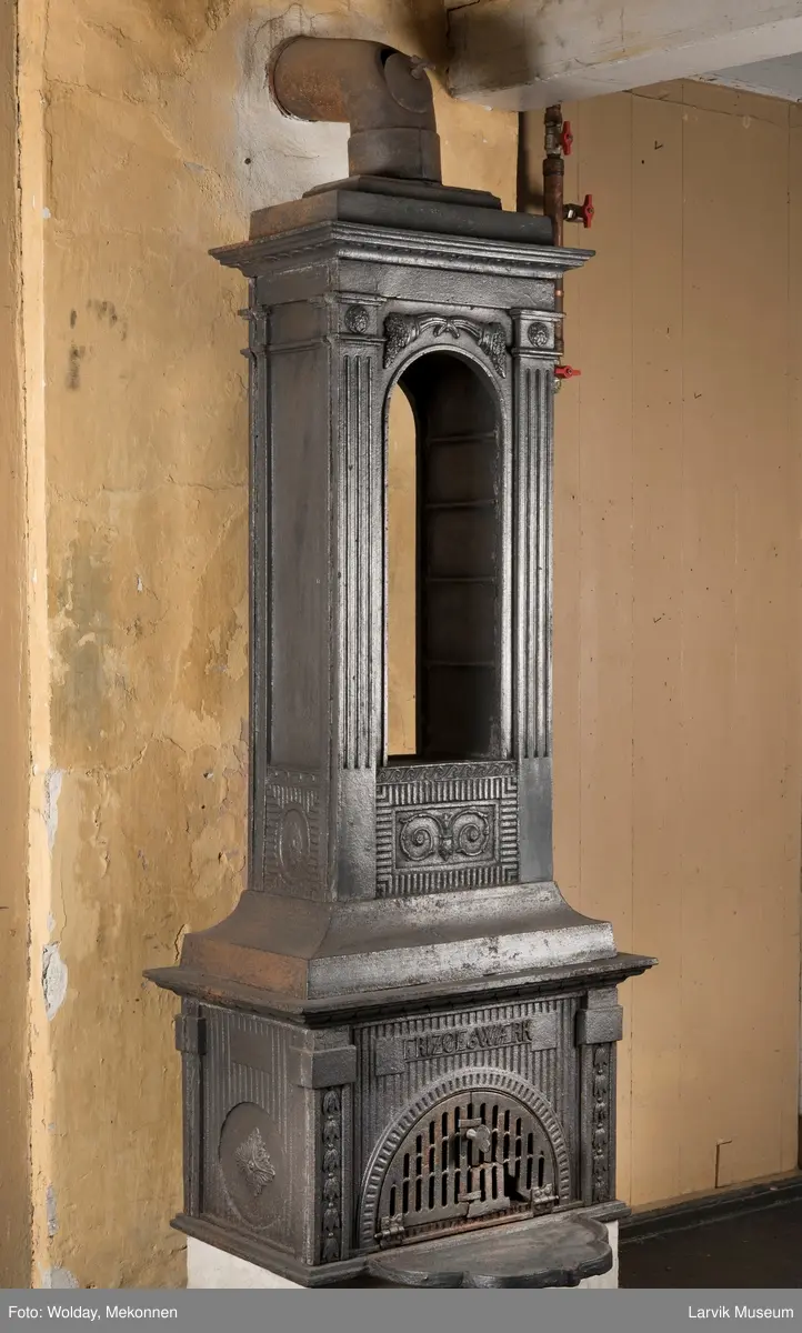 Ovn med avtrappet topp, ovalt, bølget askebrett. 
1. etasje langside: halvsirkelformet. Døren er hengslet i underkant. Over denne på plate står det Fritzøe Wærk. Riflet bunn, lisener med bladverk ved hjørnene. 1. etsje kortside: Rosett, riflet bunn, 
2. etasje langside: Rundbuet åpning, lister til 4 etasjeplater. Over åpning 2 overflødighetshorn, under palmett i riflet ramme. kannelserte pilastre i hjørnene. 2. etasjekortside: Rosett på riflet bunn, bølgemeander.