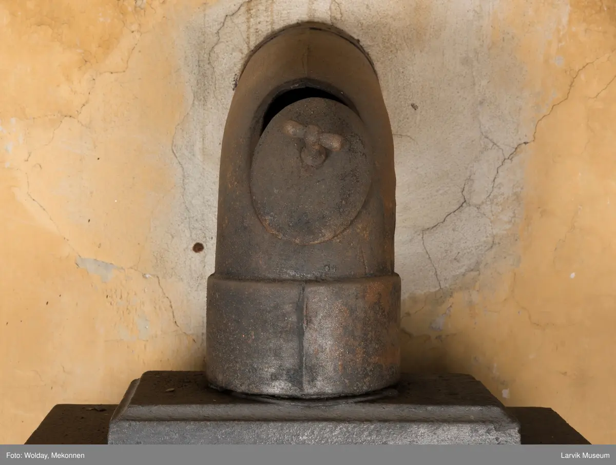 Ovn med avtrappet topp, ovalt, bølget askebrett. 
1. etasje langside: halvsirkelformet. Døren er hengslet i underkant. Over denne på plate står det Fritzøe Wærk. Riflet bunn, lisener med bladverk ved hjørnene. 1. etsje kortside: Rosett, riflet bunn, 
2. etasje langside: Rundbuet åpning, lister til 4 etasjeplater. Over åpning 2 overflødighetshorn, under palmett i riflet ramme. kannelserte pilastre i hjørnene. 2. etasjekortside: Rosett på riflet bunn, bølgemeander.