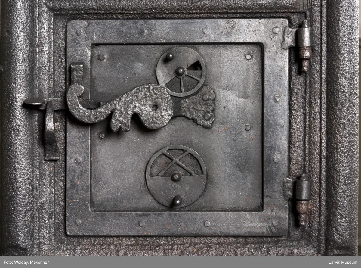 Ovnen har understell, bunnplate, sideplater, frontplate, bakplate og topp, røykkasse, røykerør og to messinghoder. Røykerøret er litt løst.