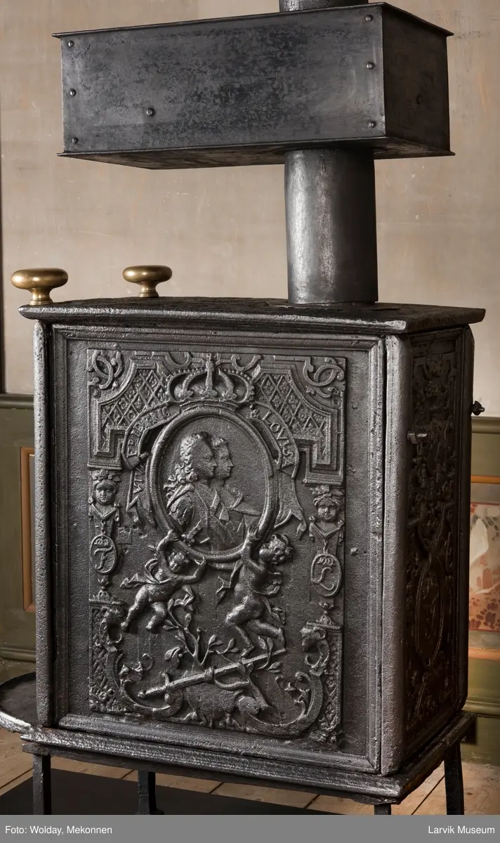 Ovnen har understell, bunnplate, sideplater, frontplate, bakplate og topp, røykkasse, røykerør og to messinghoder. Røykerøret er litt løst.