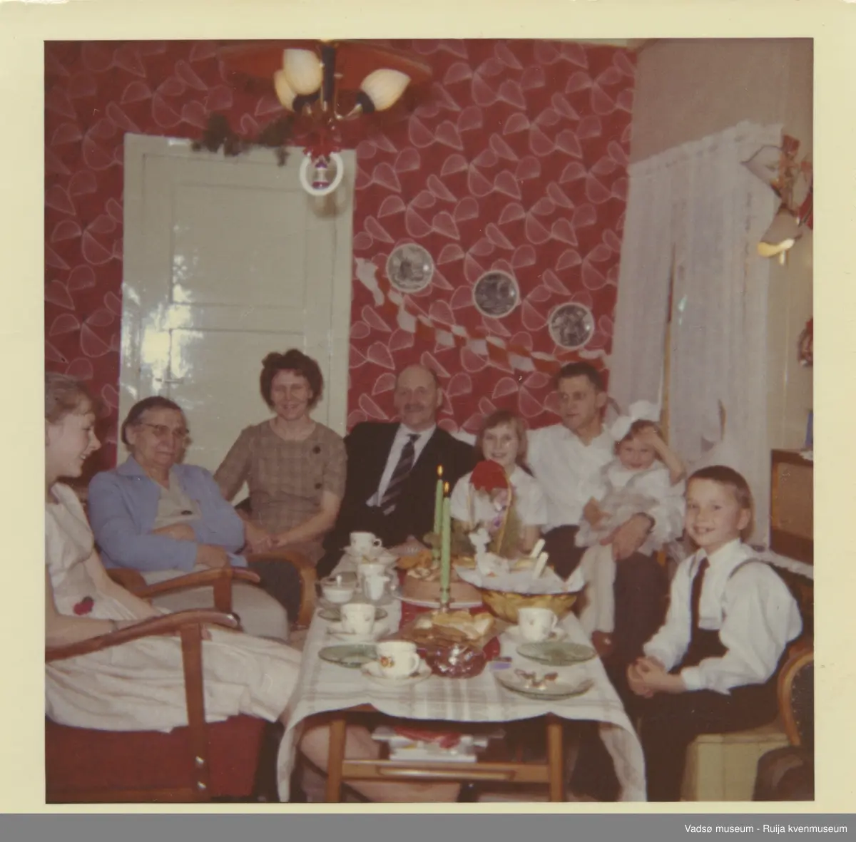 I stuen til Arne og Lilly Olsen på Kjeldsenbruket i forbindelse med julefeiring, ca. 1965. Fra venstre Gro Hansen ( før Olsen), Anna Jørstad, Lilly Olsen (før Jørstad), Daniel Jørstad, Tove O. Mikkonen, Arne Olsen, Rita Rasmussen ( før Olsen) og Roar Olsen.