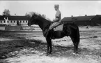 Strömsholmskursen 1916. Ridning på Strömsholm på Stallplan mellan lilla ridhuset (till vänster), officersstallet (till höger), hingstridhuset och hingststallet.