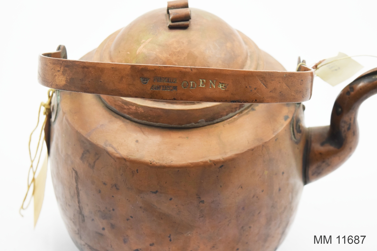 Kaffekittel av koppar. från början av 1900-talet. Försedd med lock, handtag och pip samt nedtill en avsats för spisringarna. Märkning: Oden samt två kronstämplar. Även tillverkarstämpel som lyder: J och C G Bolinder.