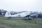 Flygplan SK 25 000 tillhörande Försökscentralen står på flygfält vid flygdagarna på Malmen 1-2 september 1962, vid firande av militärflyget 50 år. Folksamling i bakgrunden.