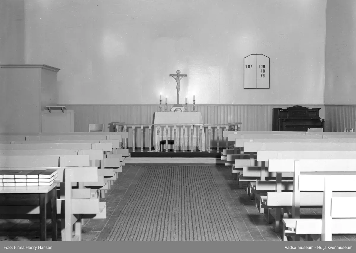 Vadsø interimkirke fotografert innvending, 1948. Fotografiet er av midtgangen med kirkebenker, alter, prekestol, orgel og salmetavle på endeveggen. Bedehuset fungerte i perioden mellom den gamle kirken brant til den nye kirken sto ferdig, som interimkirke( fra 1944 til 1958).