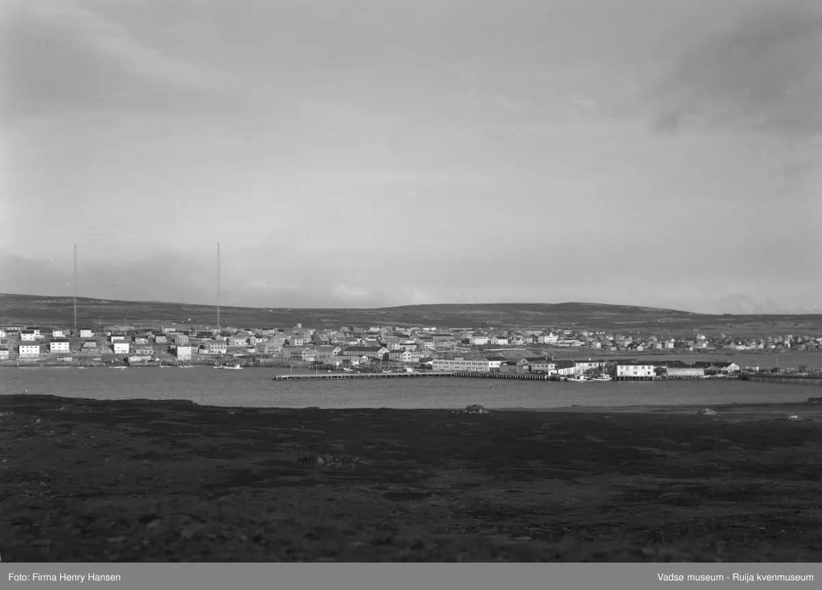 Vadsø sentrum, Ørtangen. Dampskipskaia med dampskipsekspedisjonen. Deler av Indrebyen med Midtbyen og hele Ytrebyen. Esbensen på Bakken skimtes lengst øst. Bebyggelsen som sees er også fra før krigen blant annet Kysthosptalet. Radiomastene er reist etter krigen. Bildet tatt fra Vadsøya, vest for den provisoriske broen.