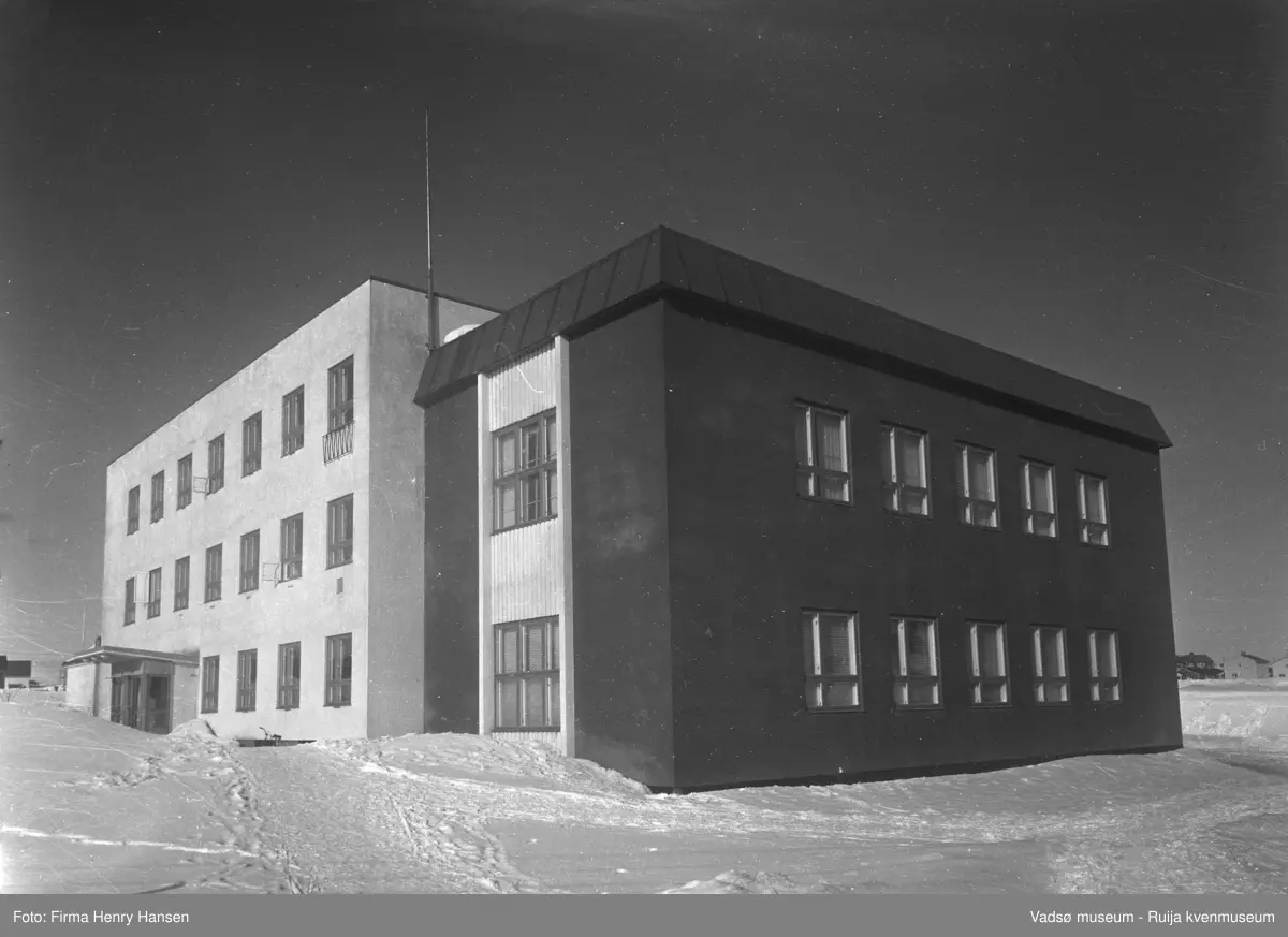 Vadsø samfunnshus. Bilder er tatt en vinterdag mot nordøst. På vestsiden av bygningen ser vi inngangspartiet. Vadsø samfunnshus' første byggetrinn var i 1957, og holdt i to og tre etasjer, bl.a. med svømmehall, kombinert fest- og gymsal, kafe og kino.