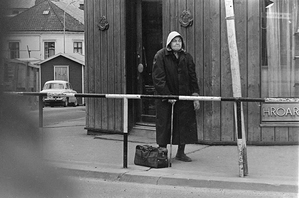 Vangsvegen, Hamar, eldre kvinne,stokk,veske, sydvest,regnfrakk, utenfor baker Hroar Nordstrøm