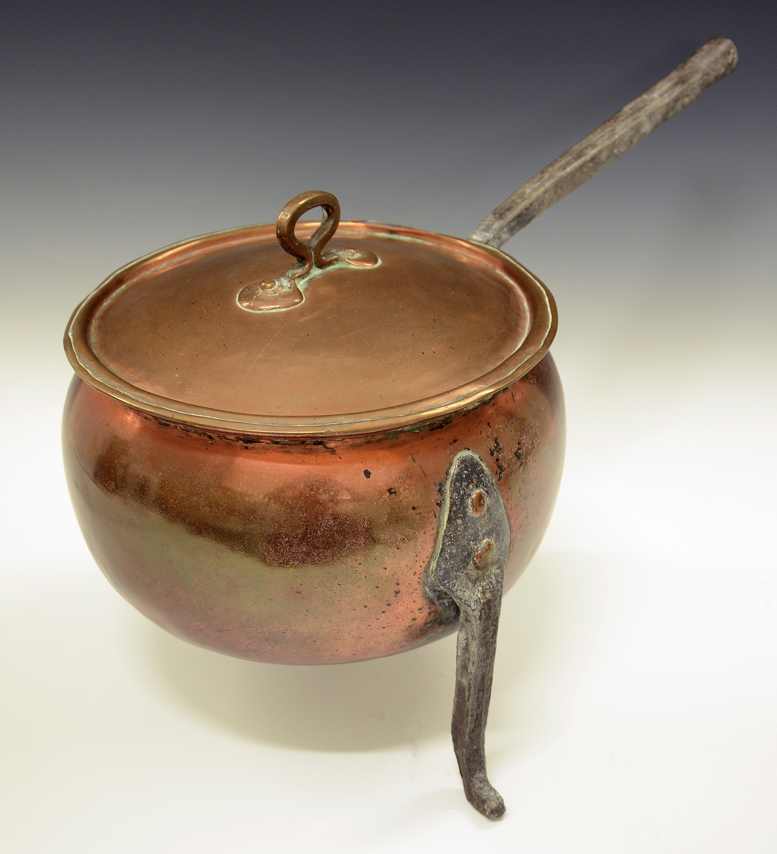 Gryte av kobber. Tre høye jernføtter og jernhåndtak, lokk med håndtak.