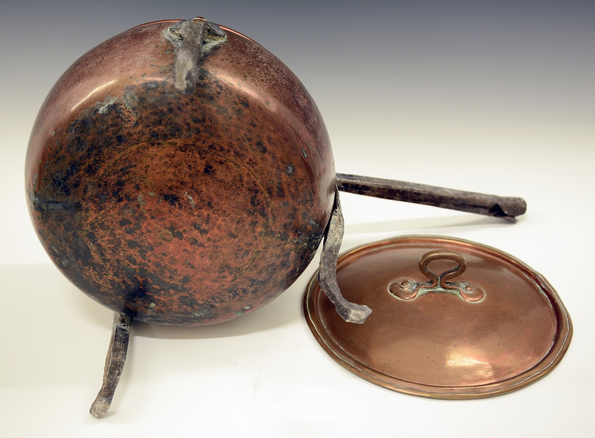 Gryte av kobber. Tre høye jernføtter og jernhåndtak, lokk med håndtak.