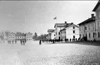 Infanterivolontärskolan Karlsborg, senare rekrytskolan för infanteriets off- och res.off. Aspiranter 1878 - 1927. Fotot taget omkr 1880. Till vänster officerspaviljongen. Den flaggprydda byggnaden var underofficers- och volontärmäss m.m. Byggnaden längst till höger underofficersvolontärernas förläggningslokaler.