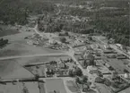 Flygfoto över Fågelfors, samhälle med villor och bostadshus samt åkrar och skog.