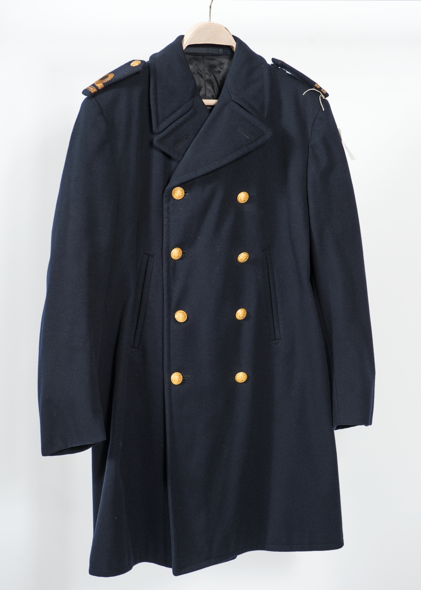 Dubbelknäppt långkavaj med 4 knappar. Vertikala ficköppningar utan lock. Axelklaffar med löjtnants gradbeteckning.