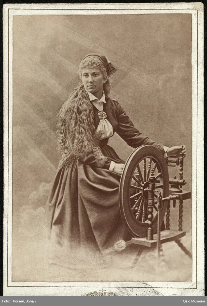 portrett, kvinne, skuespillerinne, rollebilde, Solveig i "Peer Gynt" ved uroppførelsen på Christiania Theater, sittende helfigur ved rokk, kostyme