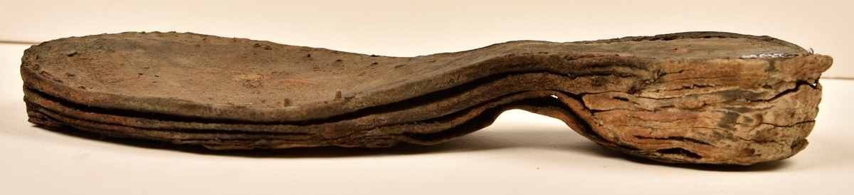 Dokumentation 1996:
Delar och fragment av sko: en skobotten samt ett fragmentariskt ovanläder, tre bitar av ett filtliknande material, ett 15-tal fragment av bottenläder samt sex mindre fragment av trä.
Skobottnen har kvarsittande tråd och träpligg. Yttersulan är ritsad. Klacken består av fem klacklappar som är placerade mellan ytter- och innersulan. Innersulans läder är mycket kraftigt, ca 6 mm tjock. Ovanlädret är sprött och fragmentariskt samt har blå och rostfärgade utfällningar.

Text in English: 
Various parts and fragments of a shoe, consisting of a sole with fragments of vamp (upper leather), three pieces of a felt-like material, some 15 fragments of sole or bottom leather and six smaller fragments of wood.
There are remains of thread and wooden pegs on the shoe sole. The outsole is channeled. The heel is made up of five heel lifts placed between the insole and outsole. The leather of the insole is very thick, ca 6 mm. The upper leather is fragile and fragmentary, and has blue and rust-coloured precipitations.

Dokumentation 2022:
Skobotten och delar av ovanläder till en öppen randsko. Tillverkade i getskinn av god kvalitet. Skapades på en rak läst och bars på höger fot. Klacken som är lagad med en läderlapp under sulan. Inga dekorationer. Det finns tecken på delaminering. Fragment från en stickad strumpa hittades inuti skon. Det finns lagningar med träpligg på sulan och hälen. Skobotten hör ihop med fyndnummer 23070.
För mer information, se Länkade filer: Uppritning

Text in english:
This is the bottom unit and upper fragments of an open shoe, made of goatskin leather of good quality, of randed construction with a patch heel, made on a straight last and worn on the right foot, with no decorative features. The bottom unit pairs with 23070. There are signs of delamination and fragments of a knitted stocking were found inside the shoe. There are pegged repairs to sole and heel.
For more information, go to Länkade filer: Uppritning