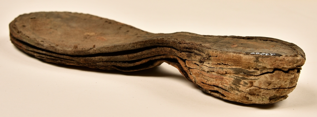 Dokumentation 1996:
Delar och fragment av sko: en skobotten samt ett fragmentariskt ovanläder, tre bitar av ett filtliknande material, ett 15-tal fragment av bottenläder samt sex mindre fragment av trä.
Skobottnen har kvarsittande tråd och träpligg. Yttersulan är ritsad. Klacken består av fem klacklappar som är placerade mellan ytter- och innersulan. Innersulans läder är mycket kraftigt, ca 6 mm tjock. Ovanlädret är sprött och fragmentariskt samt har blå och rostfärgade utfällningar.

Text in English: 
Various parts and fragments of a shoe, consisting of a sole with fragments of vamp (upper leather), three pieces of a felt-like material, some 15 fragments of sole or bottom leather and six smaller fragments of wood.
There are remains of thread and wooden pegs on the shoe sole. The outsole is channeled. The heel is made up of five heel lifts placed between the insole and outsole. The leather of the insole is very thick, ca 6 mm. The upper leather is fragile and fragmentary, and has blue and rust-coloured precipitations.

Dokumentation 2022:
Skobotten och delar av ovanläder till en öppen randsko. Tillverkade i getskinn av god kvalitet. Skapades på en rak läst och bars på höger fot. Klacken som är lagad med en läderlapp under sulan. Inga dekorationer. Det finns tecken på delaminering. Fragment från en stickad strumpa hittades inuti skon. Det finns lagningar med träpligg på sulan och hälen. Skobotten hör ihop med fyndnummer 23070.
För mer information, se Länkade filer: Uppritning

Text in english:
This is the bottom unit and upper fragments of an open shoe, made of goatskin leather of good quality, of randed construction with a patch heel, made on a straight last and worn on the right foot, with no decorative features. The bottom unit pairs with 23070. There are signs of delamination and fragments of a knitted stocking were found inside the shoe. There are pegged repairs to sole and heel.
For more information, go to Länkade filer: Uppritning
