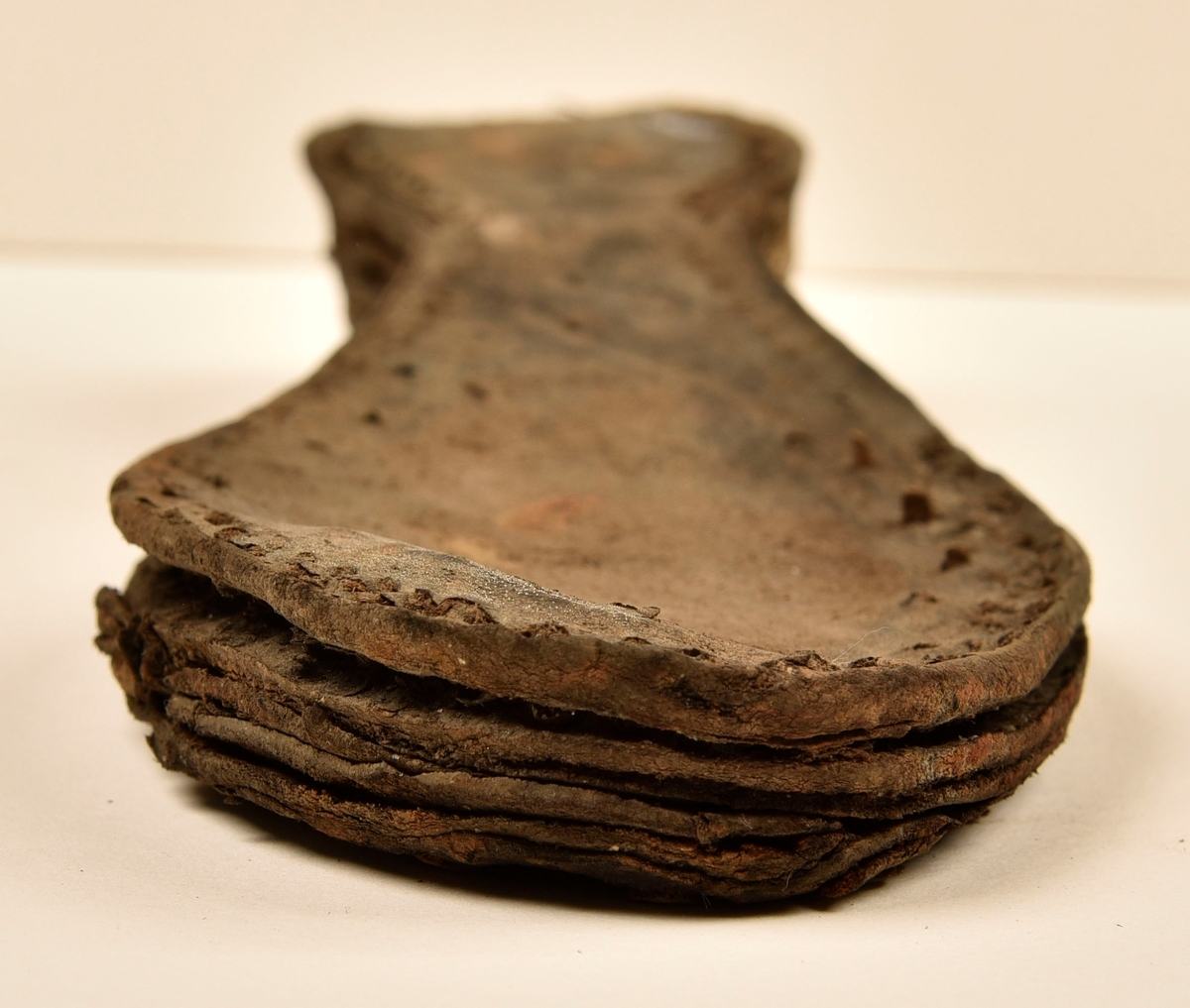 Dokumentation 1996:
Delar och fragment av sko: en skobotten samt ett fragmentariskt ovanläder, tre bitar av ett filtliknande material, ett 15-tal fragment av bottenläder samt sex mindre fragment av trä.
Skobottnen har kvarsittande tråd och träpligg. Yttersulan är ritsad. Klacken består av fem klacklappar som är placerade mellan ytter- och innersulan. Innersulans läder är mycket kraftigt, ca 6 mm tjock. Ovanlädret är sprött och fragmentariskt samt har blå och rostfärgade utfällningar.

Text in English: 
Various parts and fragments of a shoe, consisting of a sole with fragments of vamp (upper leather), three pieces of a felt-like material, some 15 fragments of sole or bottom leather and six smaller fragments of wood.
There are remains of thread and wooden pegs on the shoe sole. The outsole is channeled. The heel is made up of five heel lifts placed between the insole and outsole. The leather of the insole is very thick, ca 6 mm. The upper leather is fragile and fragmentary, and has blue and rust-coloured precipitations.

Dokumentation 2022:
Skobotten och delar av ovanläder till en öppen randsko. Tillverkade i getskinn av god kvalitet. Skapades på en rak läst och bars på höger fot. Klacken som är lagad med en läderlapp under sulan. Inga dekorationer. Det finns tecken på delaminering. Fragment från en stickad strumpa hittades inuti skon. Det finns lagningar med träpligg på sulan och hälen. Skobotten hör ihop med fyndnummer 23070.
För mer information, se Länkade filer: Uppritning

Text in english:
This is the bottom unit and upper fragments of an open shoe, made of goatskin leather of good quality, of randed construction with a patch heel, made on a straight last and worn on the right foot, with no decorative features. The bottom unit pairs with 23070. There are signs of delamination and fragments of a knitted stocking were found inside the shoe. There are pegged repairs to sole and heel.
For more information, go to Länkade filer: Uppritning