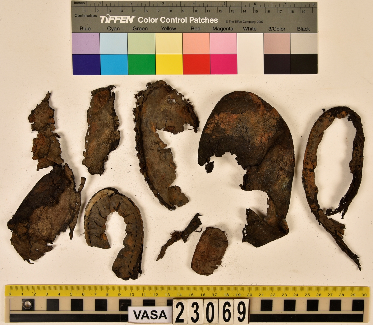 Dokumentation 1996:
Delar och fragment av sko: en skobotten samt ett fragmentariskt ovanläder, tre bitar av ett filtliknande material, ett 15-tal fragment av bottenläder samt sex mindre fragment av trä.
Skobottnen har kvarsittande tråd och träpligg. Yttersulan är ritsad. Klacken består av fem klacklappar som är placerade mellan ytter- och innersulan. Innersulans läder är mycket kraftigt, ca 6 mm tjock. Ovanlädret är sprött och fragmentariskt samt har blå och rostfärgade utfällningar.

Text in English: 
Various parts and fragments of a shoe, consisting of a sole with fragments of vamp (upper leather), three pieces of a felt-like material, some 15 fragments of sole or bottom leather and six smaller fragments of wood.
There are remains of thread and wooden pegs on the shoe sole. The outsole is channeled. The heel is made up of five heel lifts placed between the insole and outsole. The leather of the insole is very thick, ca 6 mm. The upper leather is fragile and fragmentary, and has blue and rust-coloured precipitations.

Dokumentation 2022:
Skobotten och delar av ovanläder till en öppen randsko. Tillverkade i getskinn av god kvalitet. Skapades på en rak läst och bars på höger fot. Klacken som är lagad med en läderlapp under sulan. Inga dekorationer. Det finns tecken på delaminering. Fragment från en stickad strumpa hittades inuti skon. Det finns lagningar med träpligg på sulan och hälen. Skobotten hör ihop med fyndnummer 23070.
För mer information, se Länkade filer: Uppritning

Text in english:
This is the bottom unit and upper fragments of an open shoe, made of goatskin leather of good quality, of randed construction with a patch heel, made on a straight last and worn on the right foot, with no decorative features. The bottom unit pairs with 23070. There are signs of delamination and fragments of a knitted stocking were found inside the shoe. There are pegged repairs to sole and heel.
For more information, go to Länkade filer: Uppritning