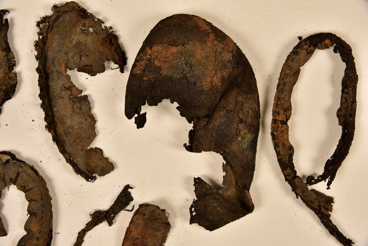 Dokumentation 1996:
Delar och fragment av sko: en skobotten samt ett fragmentariskt ovanläder, tre bitar av ett filtliknande material, ett 15-tal fragment av bottenläder samt sex mindre fragment av trä.
Skobottnen har kvarsittande tråd och träpligg. Yttersulan är ritsad. Klacken består av fem klacklappar som är placerade mellan ytter- och innersulan. Innersulans läder är mycket kraftigt, ca 6 mm tjock. Ovanlädret är sprött och fragmentariskt samt har blå och rostfärgade utfällningar.

Text in English: 
Various parts and fragments of a shoe, consisting of a sole with fragments of vamp (upper leather), three pieces of a felt-like material, some 15 fragments of sole or bottom leather and six smaller fragments of wood.
There are remains of thread and wooden pegs on the shoe sole. The outsole is channeled. The heel is made up of five heel lifts placed between the insole and outsole. The leather of the insole is very thick, ca 6 mm. The upper leather is fragile and fragmentary, and has blue and rust-coloured precipitations.

Dokumentation 2022:
Skobotten och delar av ovanläder till en öppen randsko. Tillverkade i getskinn av god kvalitet. Skapades på en rak läst och bars på höger fot. Klacken som är lagad med en läderlapp under sulan. Inga dekorationer. Det finns tecken på delaminering. Fragment från en stickad strumpa hittades inuti skon. Det finns lagningar med träpligg på sulan och hälen. Skobotten hör ihop med fyndnummer 23070.
För mer information, se Länkade filer: Uppritning

Text in english:
This is the bottom unit and upper fragments of an open shoe, made of goatskin leather of good quality, of randed construction with a patch heel, made on a straight last and worn on the right foot, with no decorative features. The bottom unit pairs with 23070. There are signs of delamination and fragments of a knitted stocking were found inside the shoe. There are pegged repairs to sole and heel.
For more information, go to Länkade filer: Uppritning