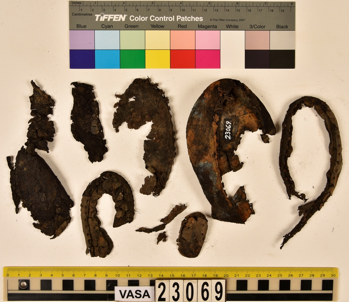 Dokumentation 1996:
Delar och fragment av sko: en skobotten samt ett fragmentariskt ovanläder, tre bitar av ett filtliknande material, ett 15-tal fragment av bottenläder samt sex mindre fragment av trä.
Skobottnen har kvarsittande tråd och träpligg. Yttersulan är ritsad. Klacken består av fem klacklappar som är placerade mellan ytter- och innersulan. Innersulans läder är mycket kraftigt, ca 6 mm tjock. Ovanlädret är sprött och fragmentariskt samt har blå och rostfärgade utfällningar.

Text in English: 
Various parts and fragments of a shoe, consisting of a sole with fragments of vamp (upper leather), three pieces of a felt-like material, some 15 fragments of sole or bottom leather and six smaller fragments of wood.
There are remains of thread and wooden pegs on the shoe sole. The outsole is channeled. The heel is made up of five heel lifts placed between the insole and outsole. The leather of the insole is very thick, ca 6 mm. The upper leather is fragile and fragmentary, and has blue and rust-coloured precipitations.

Dokumentation 2022:
Skobotten och delar av ovanläder till en öppen randsko. Tillverkade i getskinn av god kvalitet. Skapades på en rak läst och bars på höger fot. Klacken som är lagad med en läderlapp under sulan. Inga dekorationer. Det finns tecken på delaminering. Fragment från en stickad strumpa hittades inuti skon. Det finns lagningar med träpligg på sulan och hälen. Skobotten hör ihop med fyndnummer 23070.
För mer information, se Länkade filer: Uppritning

Text in english:
This is the bottom unit and upper fragments of an open shoe, made of goatskin leather of good quality, of randed construction with a patch heel, made on a straight last and worn on the right foot, with no decorative features. The bottom unit pairs with 23070. There are signs of delamination and fragments of a knitted stocking were found inside the shoe. There are pegged repairs to sole and heel.
For more information, go to Länkade filer: Uppritning