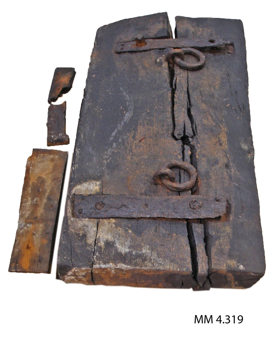 Kanonlucka (styckeport). Från vraket efter 54-kanonskeppet Nya Riga, byggt i Karlskrona år 1708. Luckan upptagen från vraket omkring år 1920. Luckans ena långsida avfasad inåt, på innersidan är den klädd med bräder, på vilken ritsar efter uppmärkning av spikhålen är synliga. Där finns också en styck större ringbult, från början har det funnits 4 stycken sådana. På yttersidan finns 2 stycken förstärkningar av järn samt 2 stycken mindre ringbultar. Luckan är sannolikt en av de aktra, den övre. De två i akterstäven befintliga portarna täcktes som regel med två luckor, en övre och en undre.