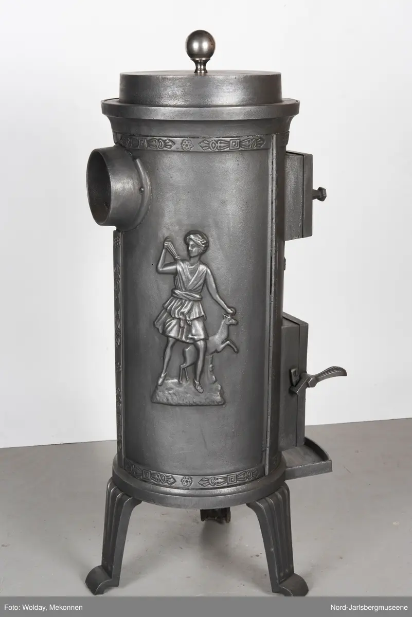 Jugendstil. Askeskuff med et slags bålmotiv, fyrdør med rosett. Relieff av klassisk motiv; Diana med hjort?