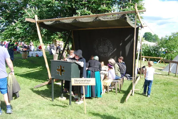 Man in medieval clothes writing with a feather pen