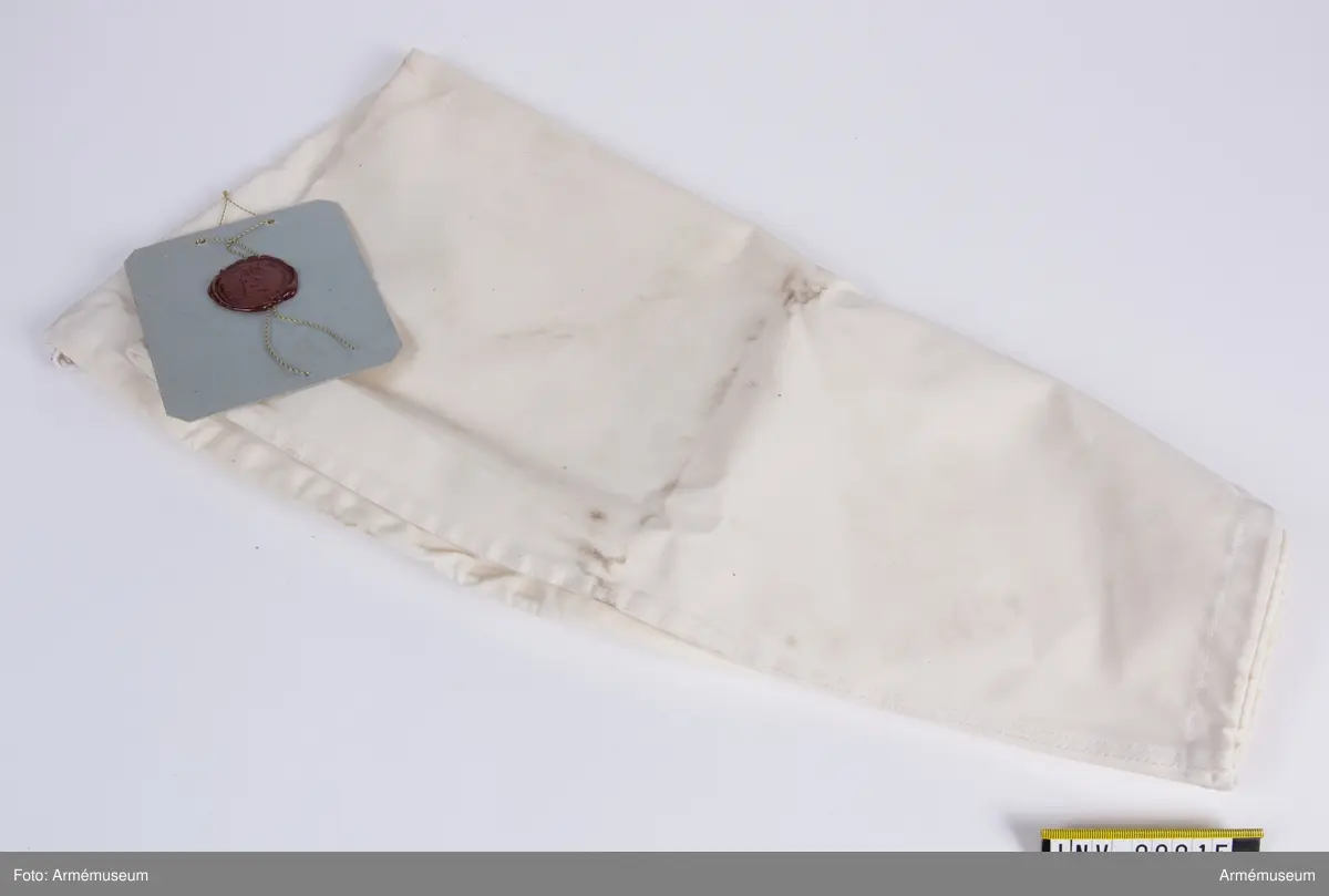 Vitt överdrag av bomull till ryggsäck m/1962. Vidhängande modellapp med text: "Kungl. Arméintendenturförvaltningen Dnr 356/60. Modell å överdrag till ryggsäck m/62. Fastställes Stockholm den 11 dec. 1962. (oläslig underskrift).