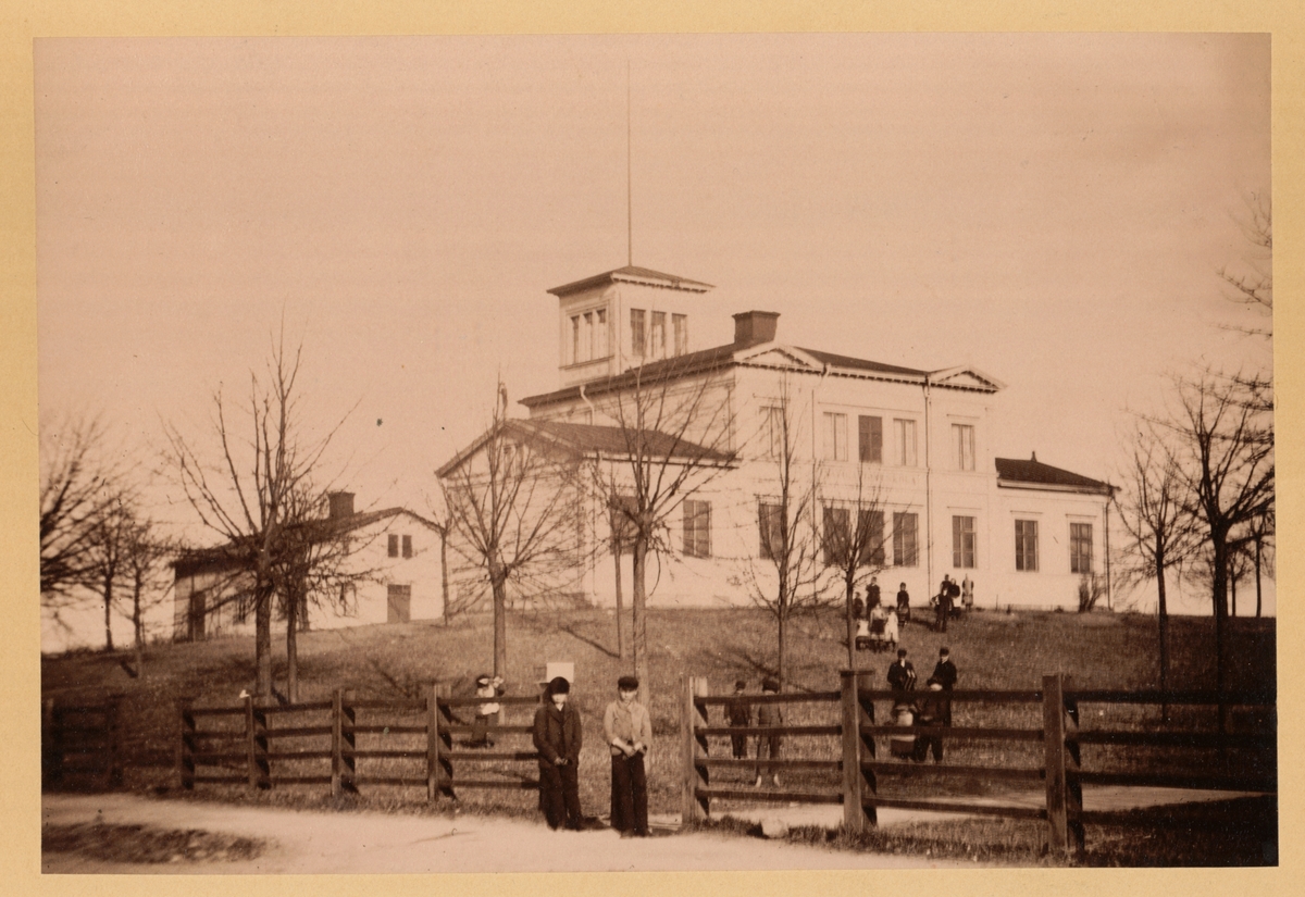 Vy från Åkaregatan mot Navigationsskolan. Byggnaden uppfördes 1862 och ritatdes av G.N. Runer. Skolan utbildade blivande sjökaptener och styrmän. Byggnaden, som Skepparsocieteten lämnat bidrag till, uppfördes i trä. Staden stod för virket. Ett så kallat observatorietorn, där eleverna fick lära sig ta ut solhöjd och göra olika beräkningar, uppfördes där. Idag ligger Polhemsskolan på platsen.