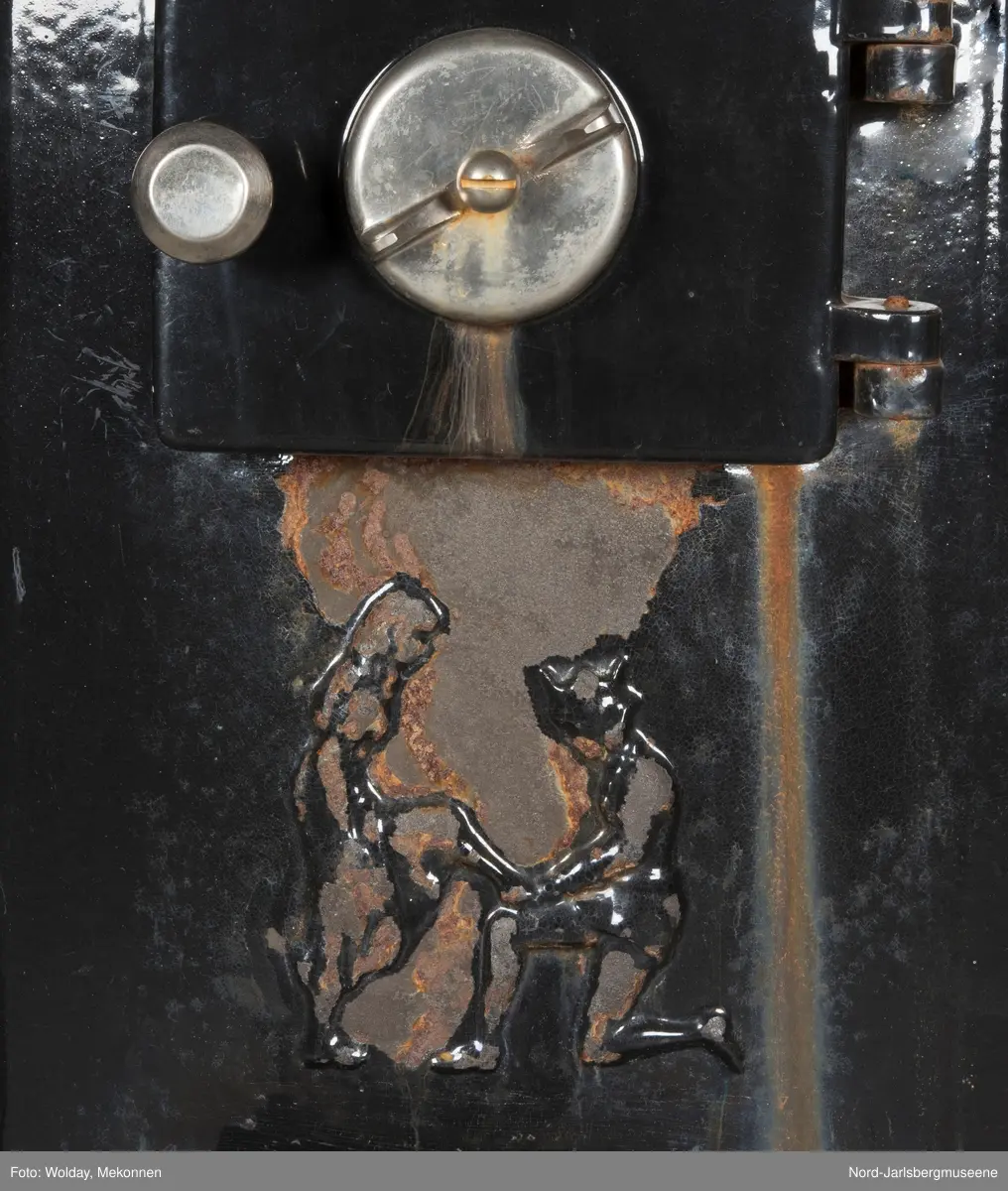 Relieffer: 1. på fronten: Askepott og prinsen som prøver om skoen passer. 2. På sidene: Askepott i grua med slottet i bakgrunnen. På grindene på dobbeltdørene til kokerom: en medaljong med grytemotiv, grinden med gjennombrutt labyrintmønster.