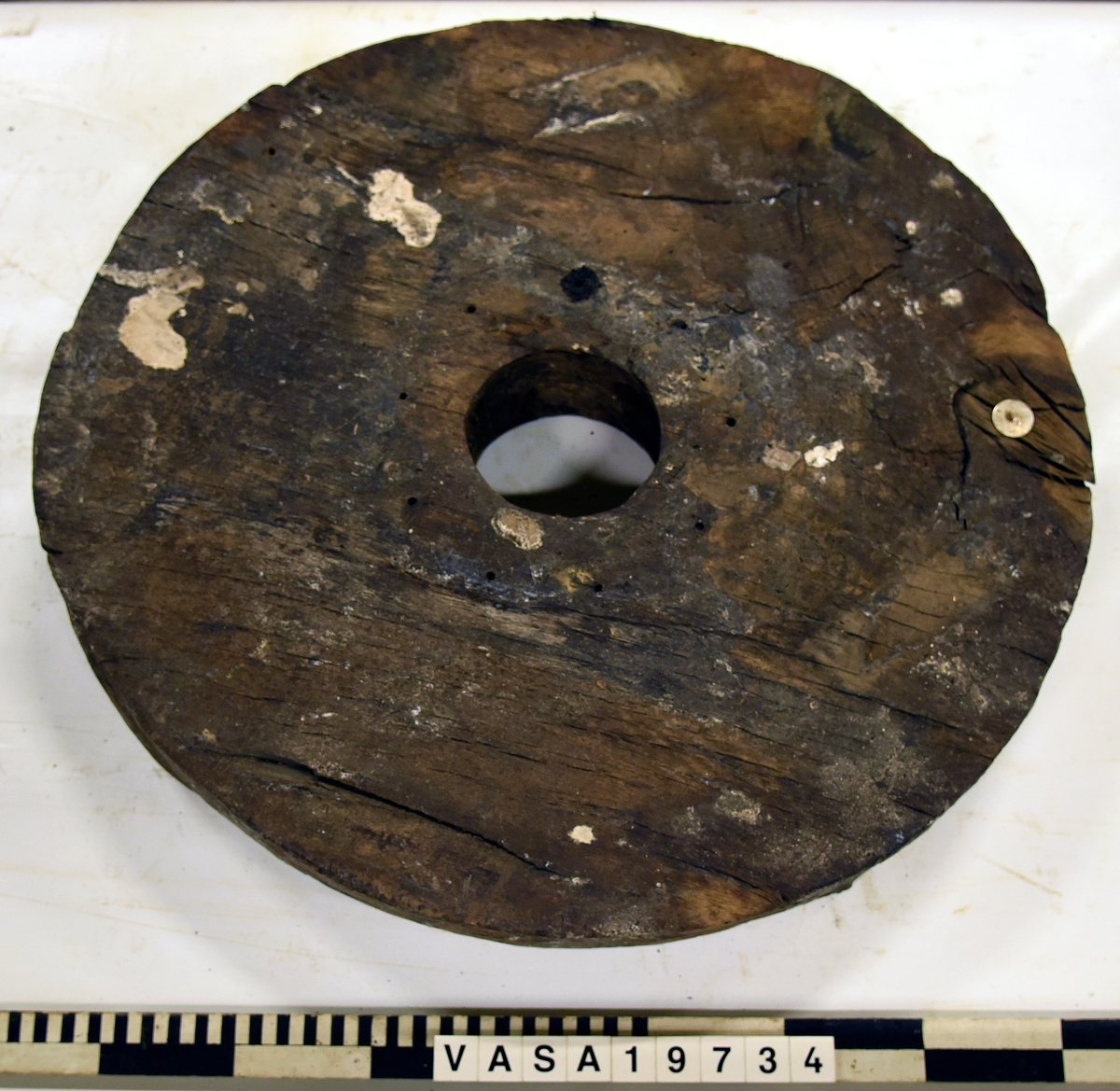 Lavetthjul fram, svåra skador och förorenad yta. Har avfasade kanter.

Front truck of a gun carriage, heavy damage and multiple impurities. Both bevelled edges.