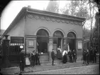 Skandinavisk-Etnografiska samlingen, senare Nordiska museet, i Davidsons paviljonger på Drottninggatan 71 A. Exteriör. Ett flertal pojkar och flickor står utanför entrén.