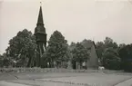 Vy över kyrkan i Fliseryd och klockstapeln samt stenmuren vid kyrkan.