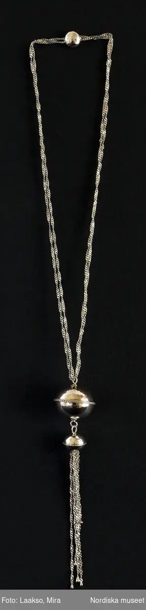 Hängsmycke av silver, "Moder jord" 925/2000, på dubbel silverkedja av platta länkar, spiralformad. Hängsmycket bestående av ett större och ett mindre klot, sammansatta med öglor av tvinnad silvertråd, det större klotet överst. Det mindre klotet avslutas nedåt med sex löst hängande kedjor av olika längd, spiralformade av samma slag som halskedjan.

Graverad på den större silverkulans nedre halva är Rosa Taikons signatur, samt silverstämplar.
/Helena Lindroth & Petrine Knight, 2014-02-18