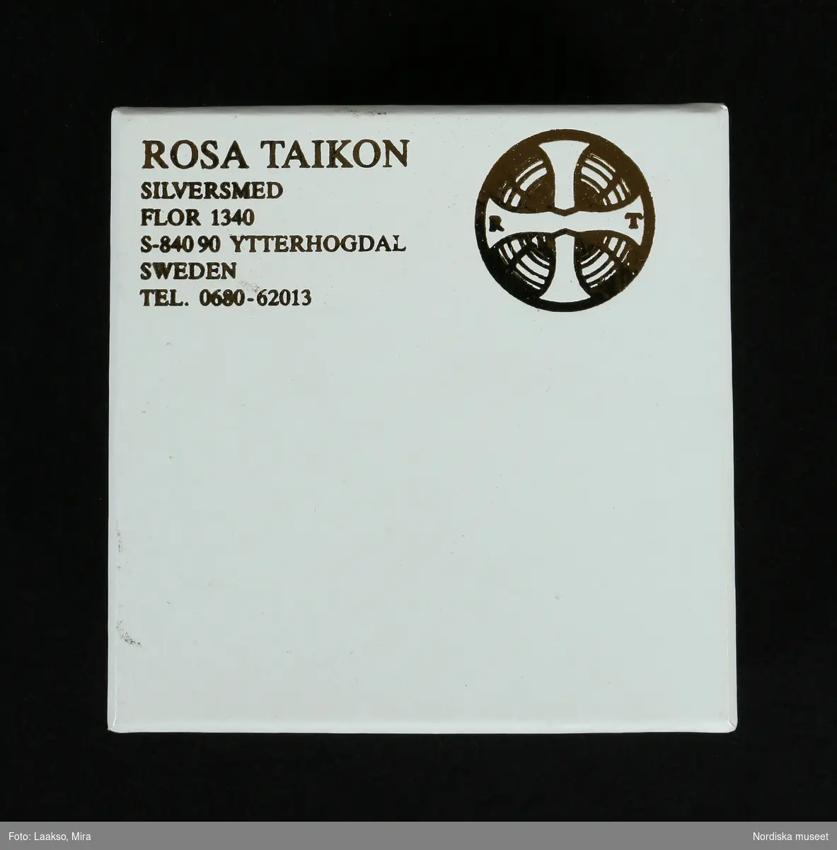 Hängsmycke av silver, "Moder jord" 925/2000, på dubbel silverkedja av platta länkar, spiralformad. Hängsmycket bestående av ett större och ett mindre klot, sammansatta med öglor av tvinnad silvertråd, det större klotet överst. Det mindre klotet avslutas nedåt med sex löst hängande kedjor av olika längd, spiralformade av samma slag som halskedjan.

Graverad på den större silverkulans nedre halva är Rosa Taikons signatur, samt silverstämplar.
/Helena Lindroth & Petrine Knight, 2014-02-18