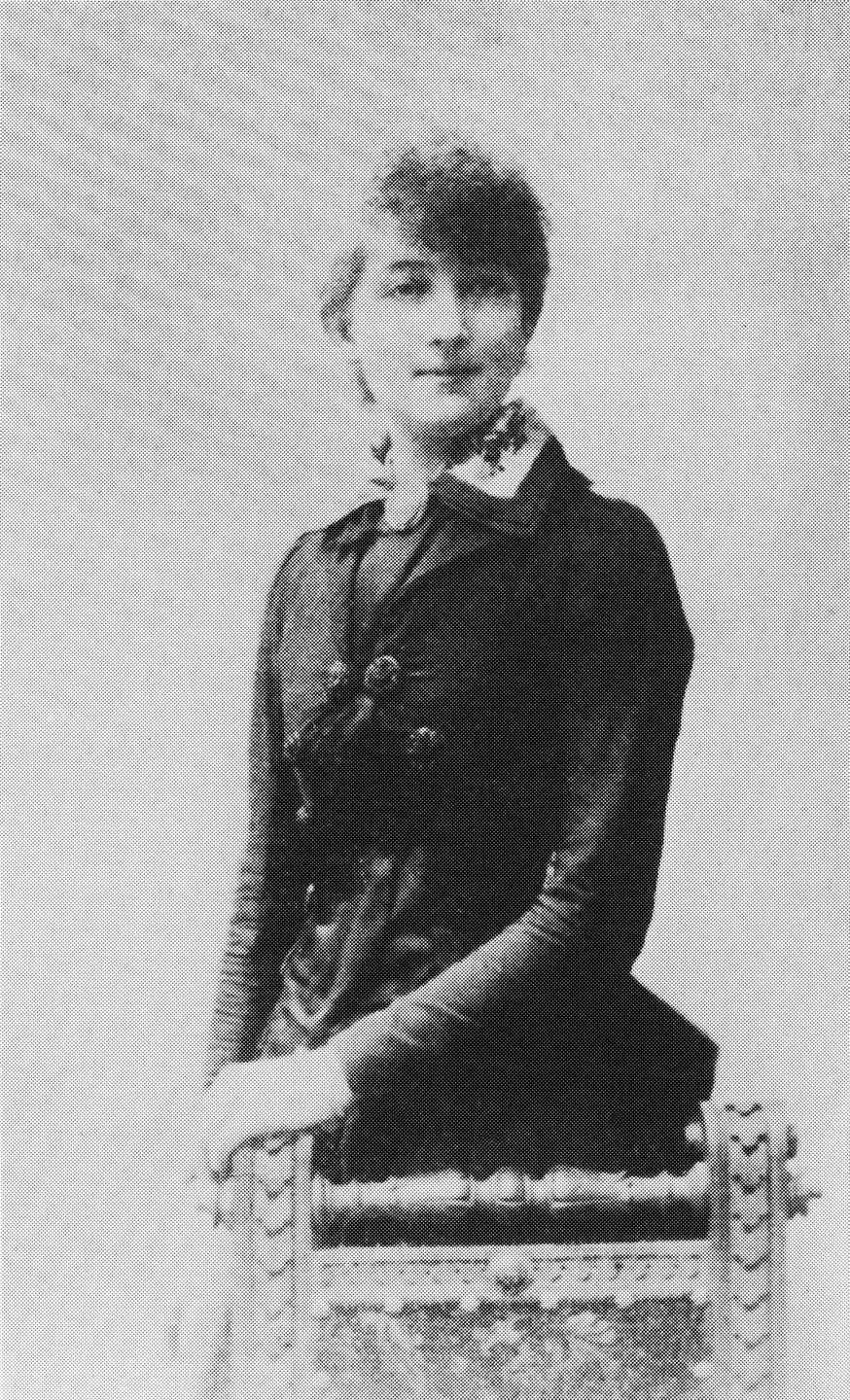 Portrett av Dagny Juel, stående ved en stol.