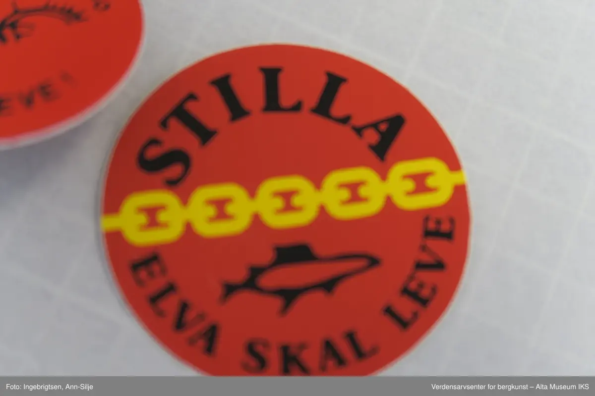 Runde merker, 19 stk.: La elva leve. Elva skal leve. Stilla. Hengemerke: 1 stk. Nålmerker: 3 stk.  Klistremerker: 6 stk. Tøymerker: 2 stk