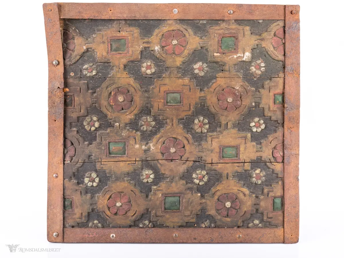 Skårede røde blomster med sirkulær innramming og grønne kvadrater med kvadratisk innramming som går i hverandre og går igjen på lokket. Innemellom disse figurene; små seksbladede hvite blomster med rød knapp. På sidene; grønne rektangler med innramming som går over i de samme røde blomstene med ramme som på lokket, men de fleste grenser mot kantene og blir halvmåneformede.