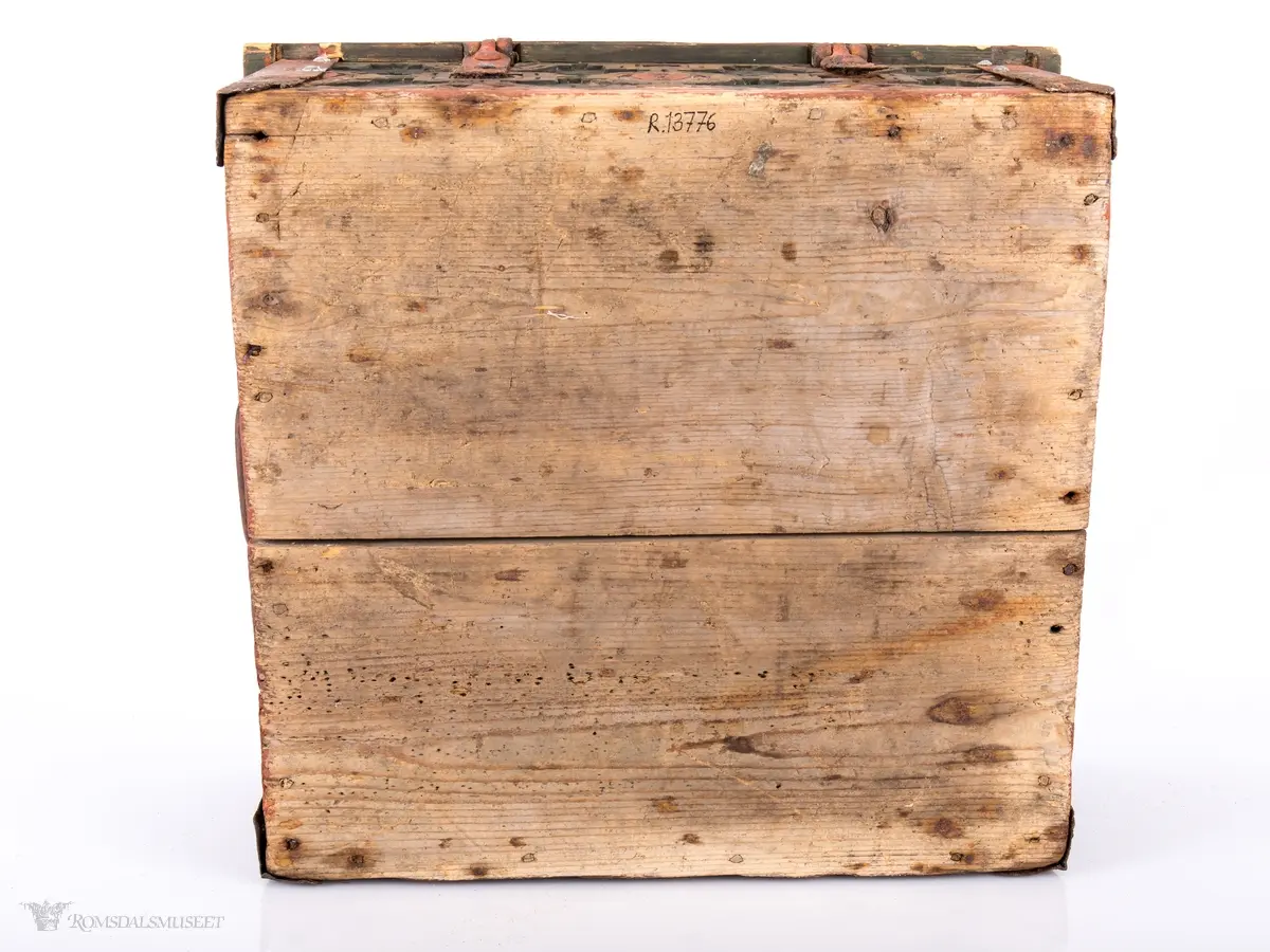 Skårede røde blomster med sirkulær innramming og grønne kvadrater med kvadratisk innramming som går i hverandre og går igjen på lokket. Innemellom disse figurene; små seksbladede hvite blomster med rød knapp. På sidene; grønne rektangler med innramming som går over i de samme røde blomstene med ramme som på lokket, men de fleste grenser mot kantene og blir halvmåneformede.