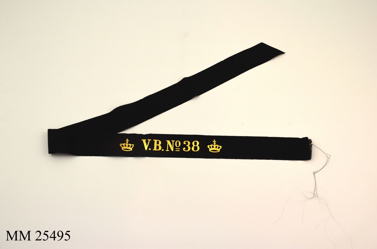 Mössband av svart sidenrips. Guldfärgad text, "V.B. NO 38", med två kronor på vardera sida.